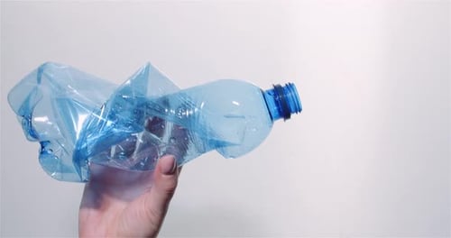 Hand Holds Crushed Plastic Bottle for Recycling