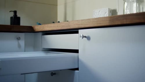 Unrecognizable Woman's Hand Closing Cupboard Drawer in Kitchen Indoors