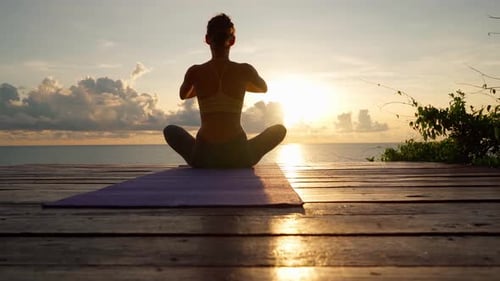 Woman Doing Yoga at Sunrise by the Sea