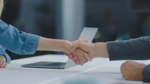 Business Handshake Over Laptop in Office Setting