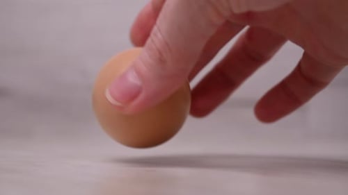 Nahaufnahme einer Köchin, die ein Hühnerei auf den Küchentisch legt. 4K