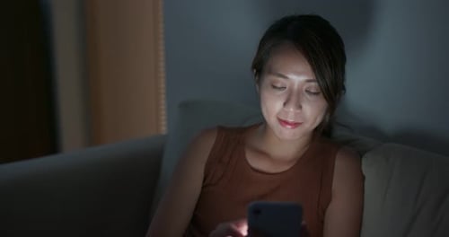 Woman Using Smartphone on Couch at Night