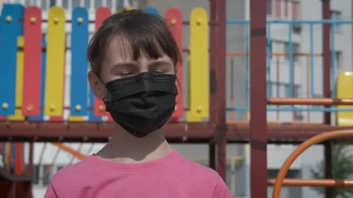 Niño enmascarado en el patio de recreo.