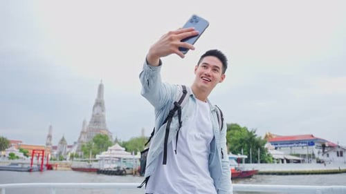 Asian man backpacker using mobile phone take picture of Buddha temple.
