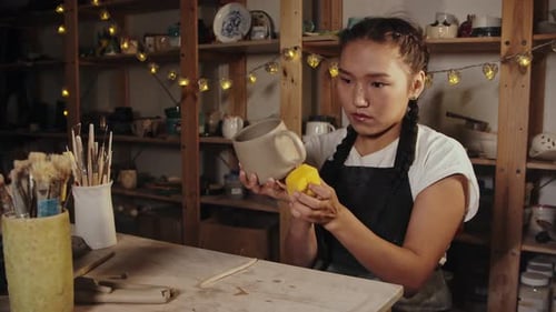 Young Woman Smoothing Ceramic Mug in Pottery Studio