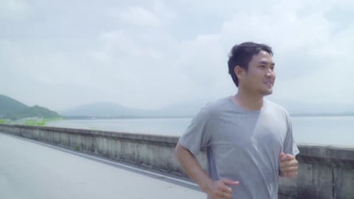 Asian runner man run and jog on street, Healthy handsome young sporty male exercise near lake.