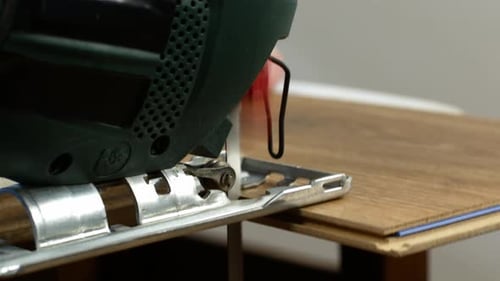 A carpenter cuts wood with an electric jigsaw. Repair work, wood sawing. 4K video close-up.