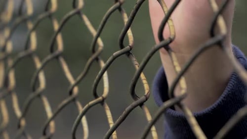 Closeup View of Young Woman's Hands Slip on the Metal Mesh at Fenced Area