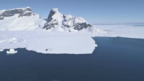 Vol aérien au-dessus de l'océan Antarctique jusqu'à la terre enneigée