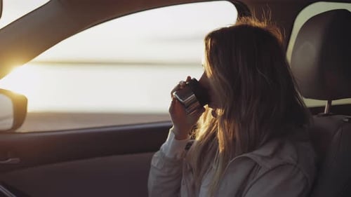 Woman Inside the Car is Drinking Coffee From the Thermos Cup Adoring Sunrise