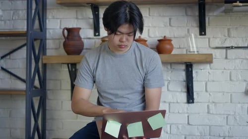 Young Adult Typing on Laptop Indoors