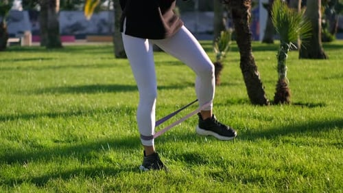 Woman Exercising with Resistance Band Outdoors on Lawn