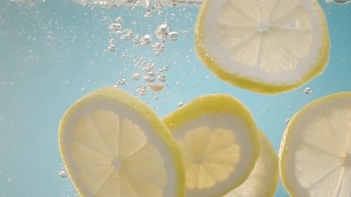 Lemon Slices Falling Into Clear Water