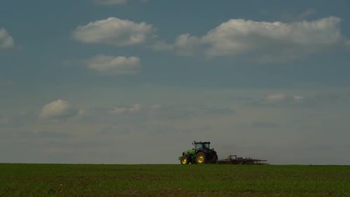 Landwirtschaftlicher grüner großer Traktor im Feld pflügt mit einem Pflug