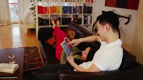 Relaxed Couple Sharing Tablet Device in Living Room