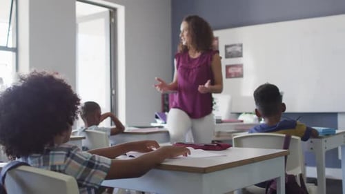 Video of caucasian female teacher and diverse school children studying in classroom