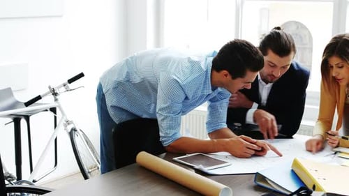Architects Reviewing Blueprints in a Bright Modern Office