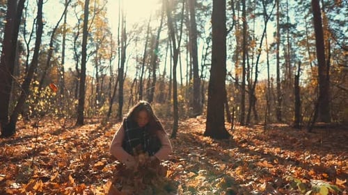 Funny Woman Is Collecting From Ground Dried Leaves and Tossing Them in Park