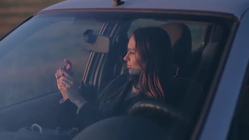 Woman Using Phone in Car During Sunset