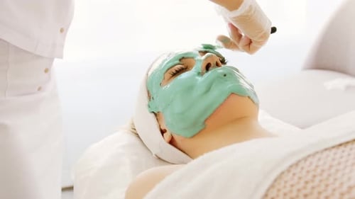 Cosmetologist applying face alginate beauty green mask.