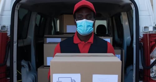 African man courier delivering packages with truck while wearing safety face mask
