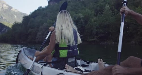 Couple Kayaking on Calm Lake Surrounded by Mountains