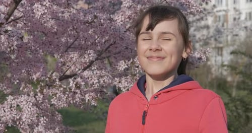 Girl Sneezing Next to Blossoming Spring Tree
