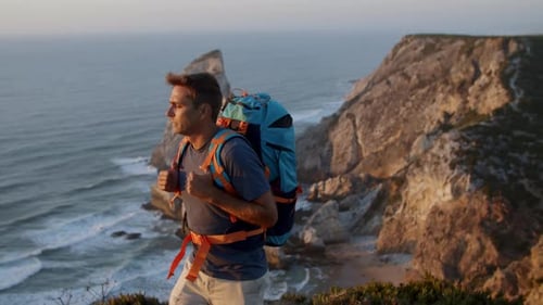Active Male Backpacker Walking Along Cliff