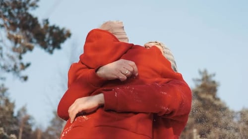Young Happy Couple in Red Sweaters in the Winter Forest Look at Each Other and Smile