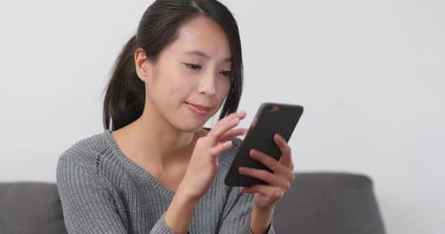 Woman Using Smartphone on Sofa Indoors