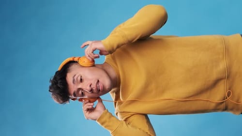 Young Adult Enjoying Music with Headphones on Blue