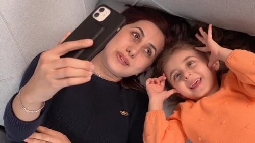 Mother and Child Smiling Together on Couch with Phone