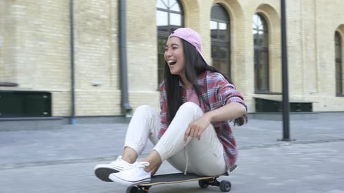 Asian woman having fun snd riding on the skateboard
