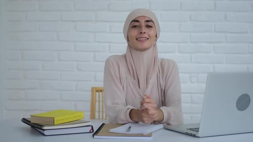 Smiling Woman at Desk with Laptop and Notebooks