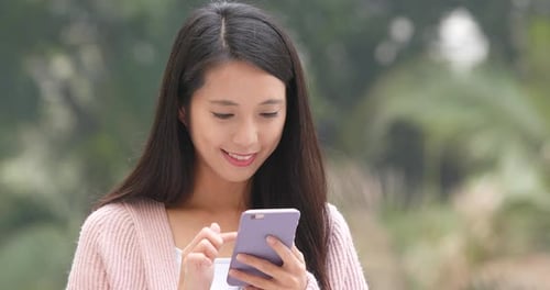 Smiling Woman Uses Smartphone in Park Close-Up