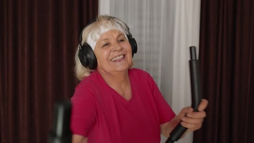 Enthusiastic Senior Woman Exercises on Stationary Bike at Home