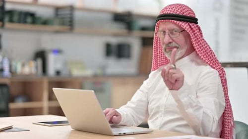 Adult Man Types on Laptop, Raises Warning Finger
