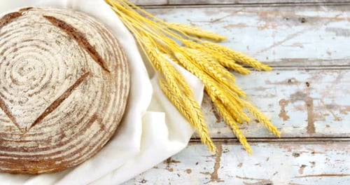 Fresh Bread Loaf with Wheat on Wood Surface