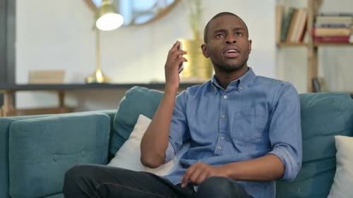 Young Adult Talking on Mobile Phone on Couch