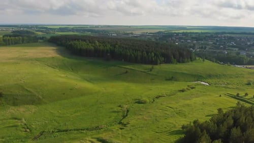 Green Open Field and Forest and Village on the Background