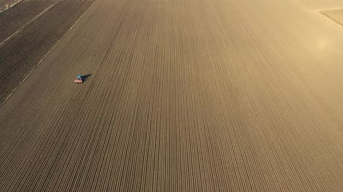 Tractor Working on Brown Flat Field
