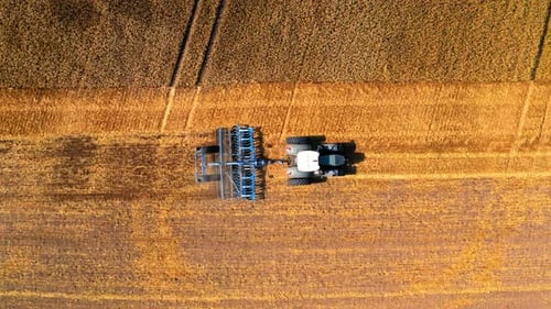 Aerial view of tractor plowing field after harvest in autumn