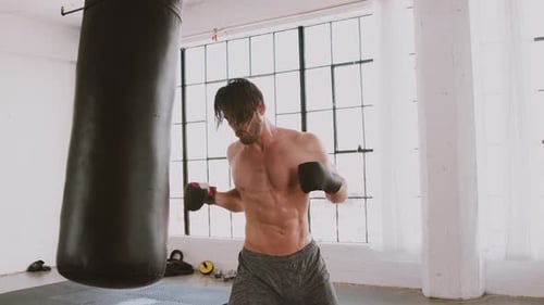 Man Punches Heavy Bag in Gym