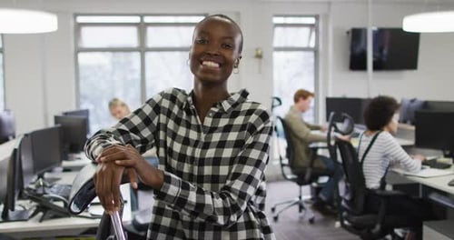 Portrait of smiling african american creative businesswoman sitting by desk in modern office