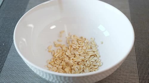 Oats Being Poured Into White Bowl Close Up