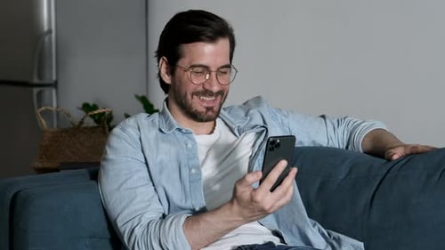 Close Up Of a man with Glasses Smiling Using a Smartphone Talking Online call with Friends