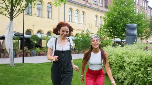Two Smiling Women Running in Urban Park