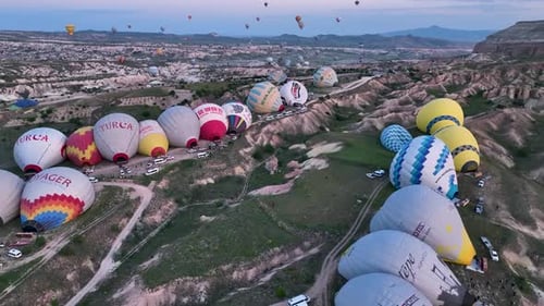 Hot air balloons fly over the mountainous landscape of Cappadocia, Turkey.