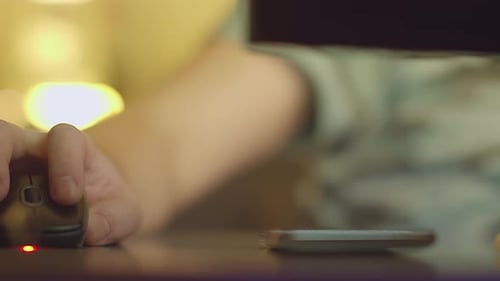 A Man Works at Home on a Computer and Answers Messages on His Mobile Phone Evening Light
