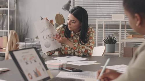 Multiethnic Female Colleagues Discussing Business Charts and Graphs